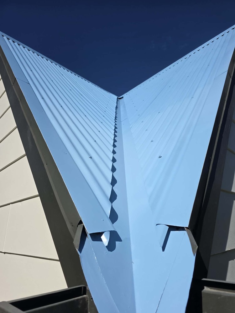 A bright blue painted roof valley against a deep blue sky